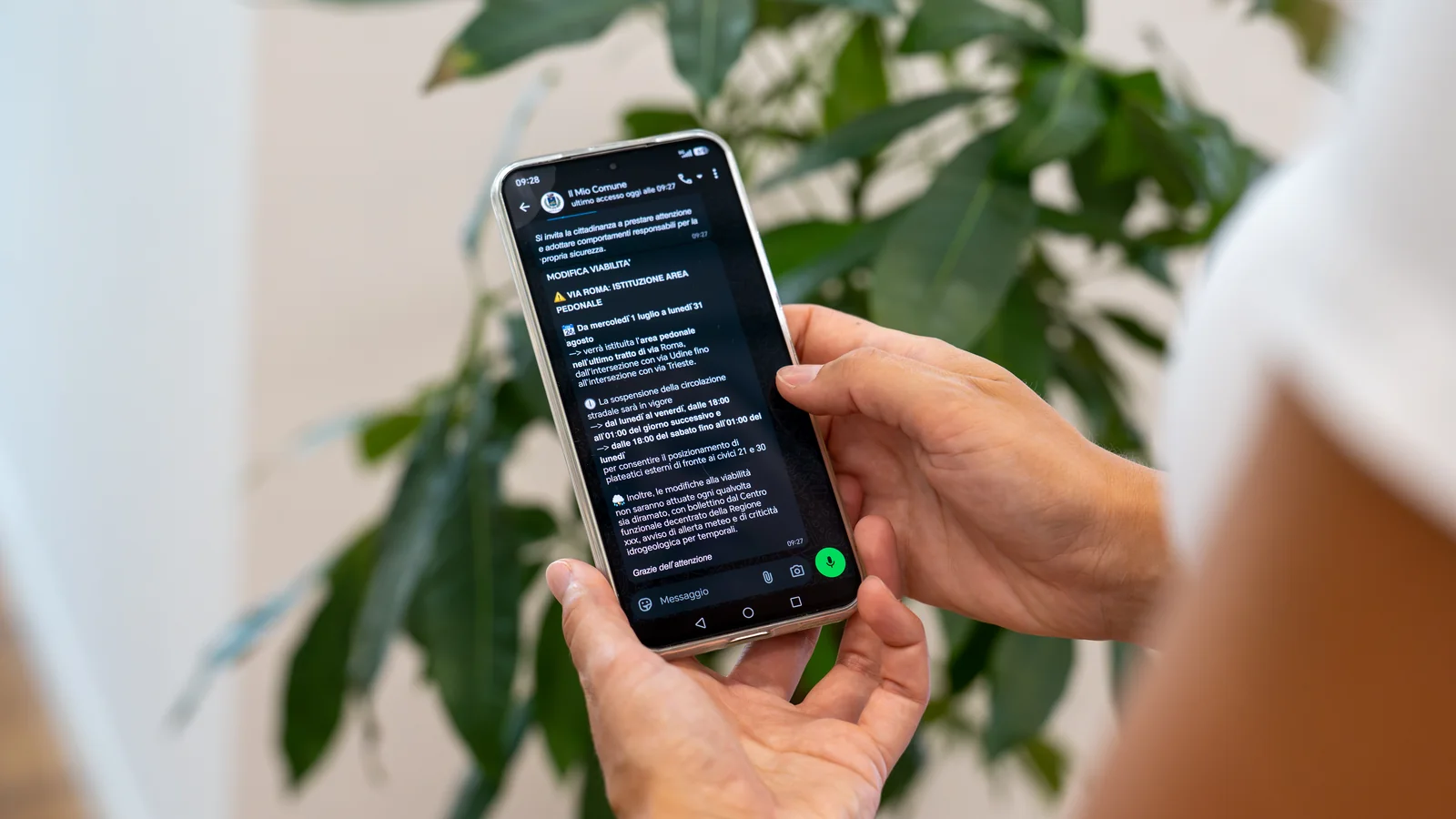 Un cittadino legge sul telefono un avviso del Comune ricevuto su WhatsApp